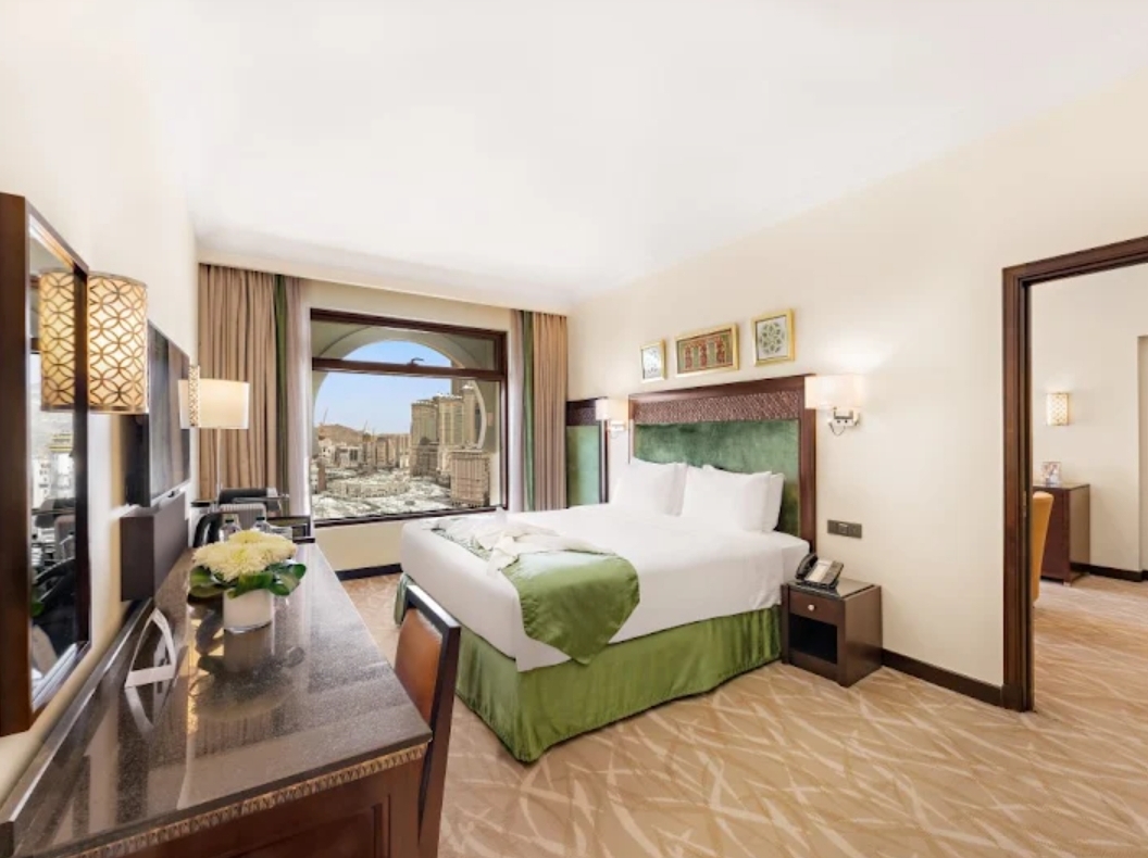 Spacious 5 star hotel room with a green bedspread and city view