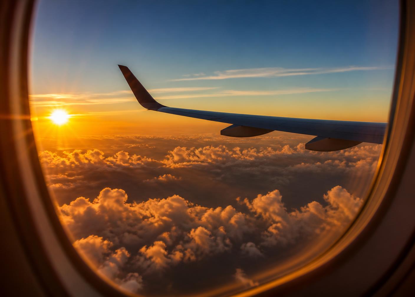 An aeroplane wing above golden clouds at sunset